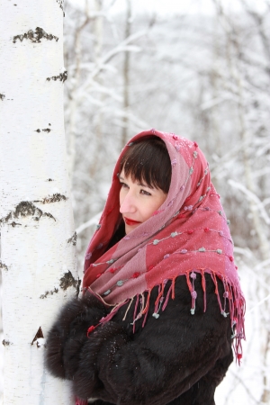 Thoughtful girl in a pink scarf in winter birch forest nearの写真素材