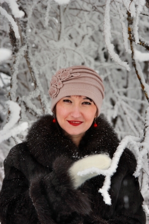 Portrait of a cute girl in a winter snow-covered branches of the forest nearの写真素材