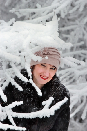 Girl in winter coat and hat near the snow-covered treeの写真素材