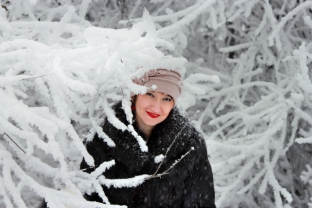 Cheerful girl looks out of a snow-covered treeの写真素材
