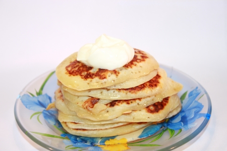 Small sweet pancakes with sour cream and honeyの写真素材