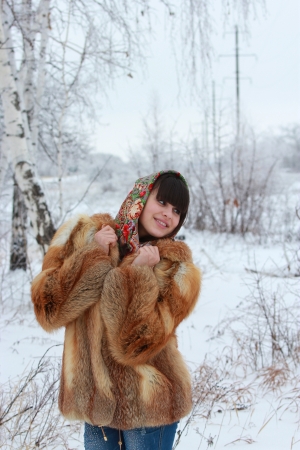 Girl in fox fur coat and a beautiful shawl in a winter forest looking awayの写真素材