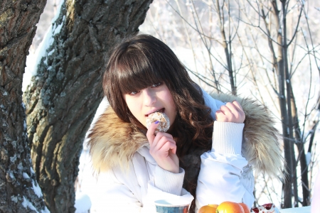 Girl resting in a winter forest, eating cake and drinking teaの写真素材