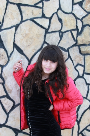 Beautiful girl in a black dress near a stone wallの写真素材