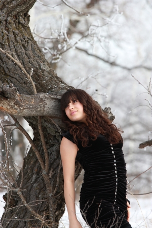Young brunette dreaming near the tree in a black dressの写真素材