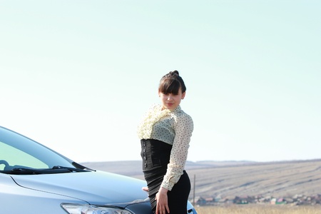 Beautiful brunette stands near a car outdoorsの写真素材