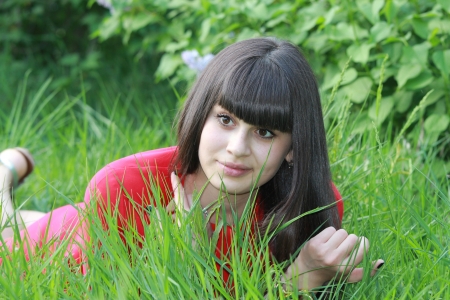 A young girl in a red dress lying on the grassの写真素材