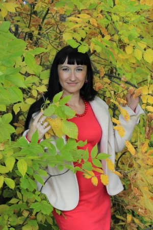 Smiling girl in autumn forest near foliageの写真素材