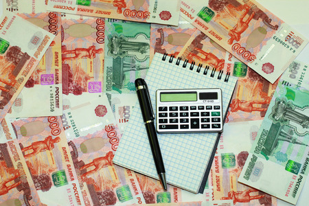 Pen, notepad and calculator lying on a background of Russian moneyの写真素材