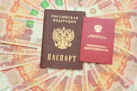 Passport and a pension certificate on the background of five thousandth moneyの写真素材