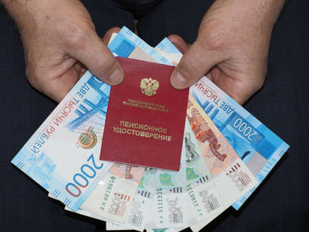 Pension: Pension certificate, Russian passport in men's hands against the background of Russian moneyの写真素材