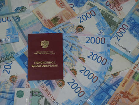 Receiving a pension. The pensioner's certificate is on Russian moneyの写真素材