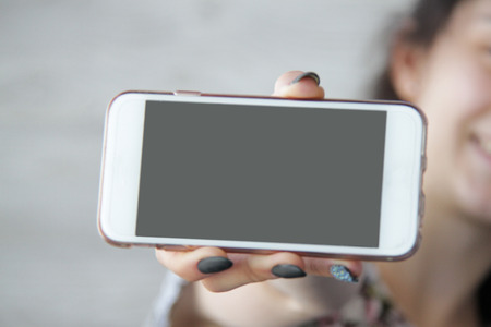 The image a close up of female hands with phone, the girl on a background.の写真素材