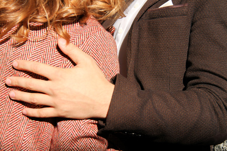 Guy and girl. The guy embraces the hand the girl. Girl's back. Man's hand. Macrophoto.の写真素材