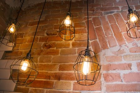 hanging from the ceiling are a few light bulbs in a minimal black lattice metal shade against a...