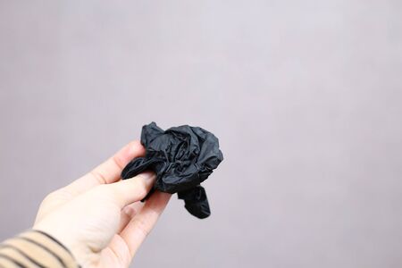 crumpled trash from a black latex glove in the hands of a girl. close-up, light background.