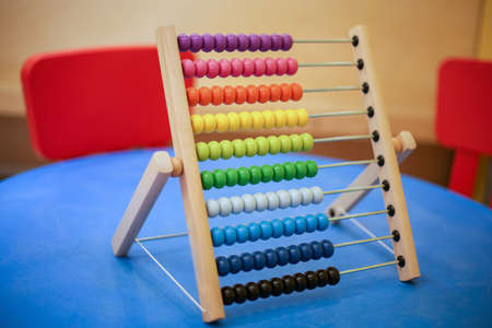 children's colored abacus in a wooden outline on a blue table.