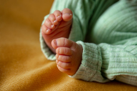 small legs of a newborn baby in green pants on a yellow background.の写真素材