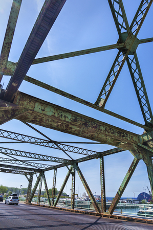 The underside view of an old rusted bridge in Toronto against blue sky.の写真素材