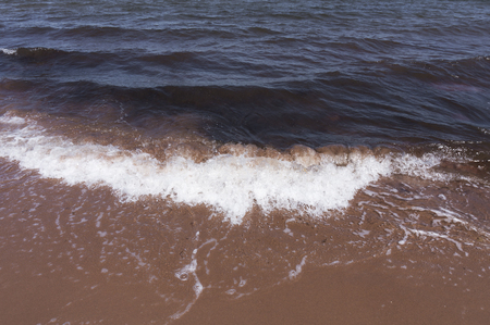strong sea wave with white foam on sand beachの写真素材