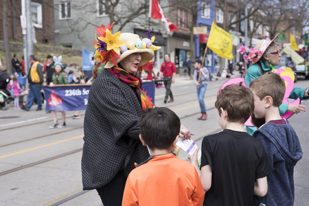 woman in Easter costume distributes gifts to children along the Queen Street East in the Beaches Easter Parade 2017.のeditorial素材