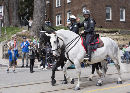 Toronto mounted police officers wave to viewers along the Queen Street East during the Beaches Easter Parade 2017のeditorial素材