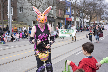 woman in Easter costume distributes gifts to children along the Queen Street East in the Beaches Easter Parade 2017のeditorial素材