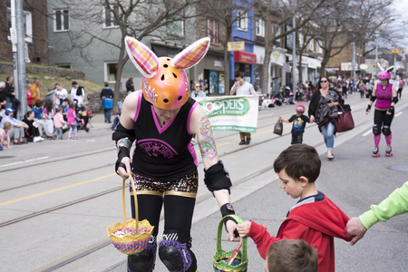 woman in Easter costume distributes gifts to children along the Queen Street East in the Beaches Easter Parade 2017のeditorial素材