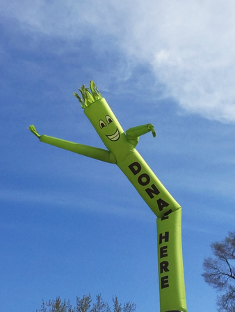 Donate Here inflatable cute cartoon character dancing against blue skyの写真素材