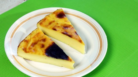 Dessert: Piece of Parisian Flan or French Custard Pie on white plate and green background