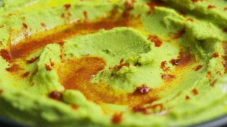 Close up of avocado hummus topped with olive oil and paprika