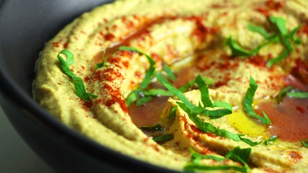Homemade hummus with olive oil and paprika in a black bowl on a white background. Close upの写真素材
