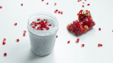 Chia Seeds Pudding with Pomegranate Seeds in a Glass Jar on a White Background. Healthy Food Concept. Vegan Foodの写真素材