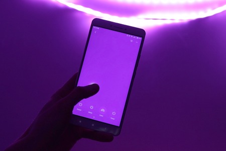 Smart Home: Man Controlling Lights With App On His Phone. Innovation Technology