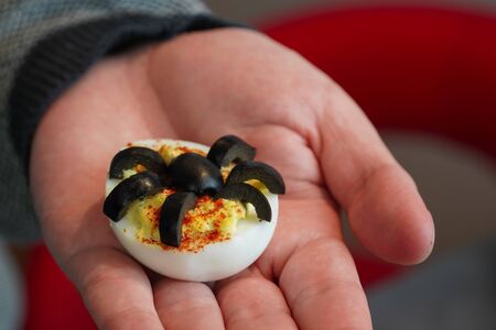 Deviled Eggs topped with Olive Spiders in a Hand. Healthy Halloween Food