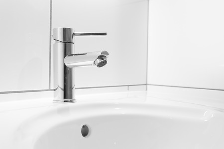 Faucet and white basin in a hotel bathroomの写真素材