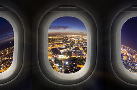 Composite image of city at night through airplane windowの写真素材