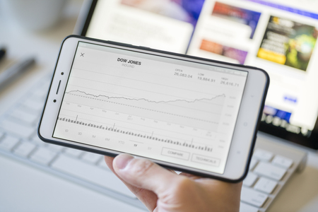 Analyzing the chart of Dow Jones Industrial Average on a smartphoneのeditorial素材