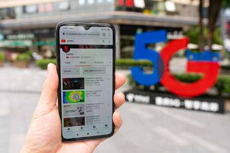 Using smartphone in front of 5G sign
