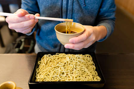 Woman enjoying Japanese soba noodle with dipping sauce
