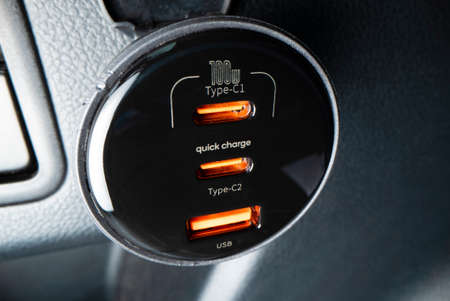 Close-up view of powerful car charger with USB type C and type A ports, shot with macro probe lensの写真素材