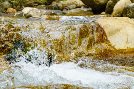 Water flowing over rocks in a mountain stream. Beautiful natural background.