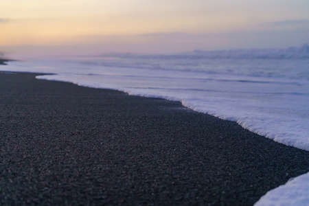 Black sand beach in winter season at sunset time. Beautiful natural background.の写真素材