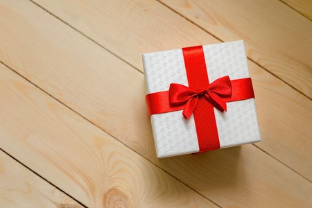 Gift box with red ribbon on wooden background.の写真素材