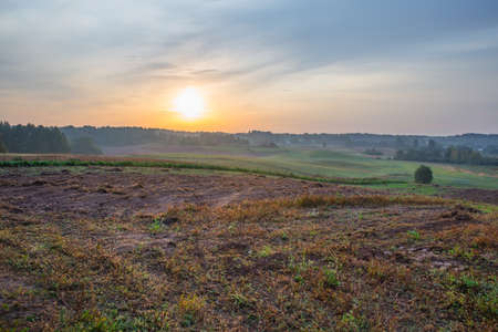 City of Kraslava, Latvia. Early morning with sunlight, meadow, trees and fog. Nature photo.の写真素材