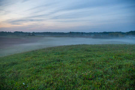 City of Kraslava, Latvia. Early morning with sunlight, meadow, trees and fog. Nature photo.の写真素材