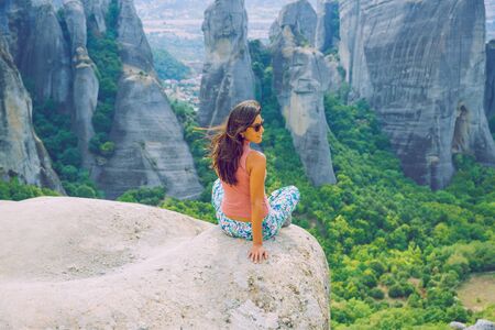 City Meteora, Greek Republic. Big mountains and girl sit on rock. 12. Sep. 2019. Travel photo.の写真素材