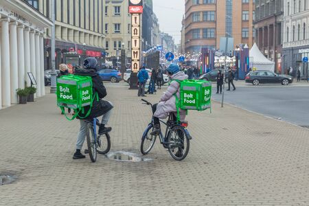 City Riga, Latvia. Fast delivery of food by bicycle. A cyclists stands on the street with a food box. 18.01.2020のeditorial素材