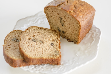 A loaf of walnut bread, sliced on a white plate
