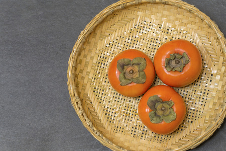 Fresh ripe persimmons on Japanese bamboo basketの写真素材